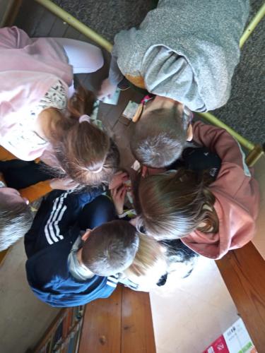Dzieci na podłodze układają puzzle z zagadką, głowy mają pochylone ku podłodze