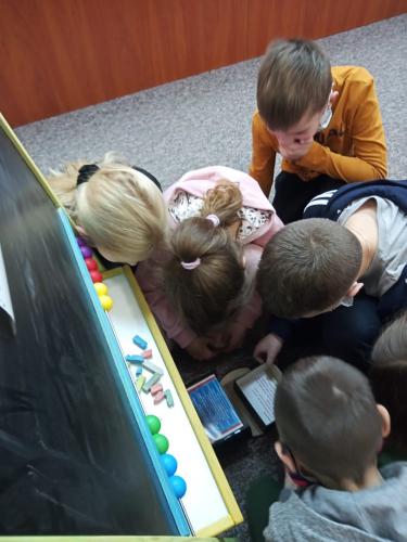 Pięcioro dzieci patrzy na szkatułkę z zagadką, czytają tekst z kartki