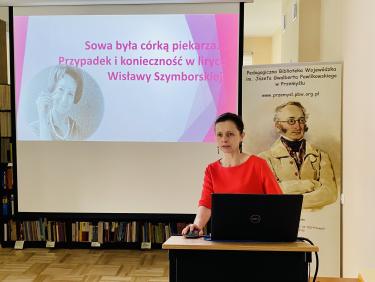 dr Małgorzata Wilgucka - prelegentka podczas wykładu, w tle slajd prezentacji