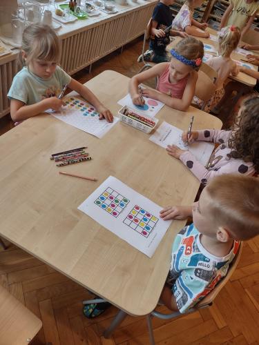 Przedszkolaki siedzące przy stoliku rozwiązują sudoku z kropką