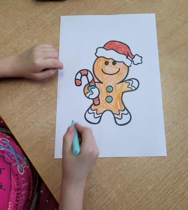 Kolorowanka z wydrukowanym piernikiem, ręka dziecka które maluje.