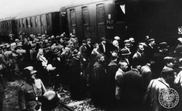 Załadunek więźniów do wagonów. Rampa towarowa przy dworcu kolejowym w Tarnowie, 14 czerwca 1940. Domena publiczna. Źródło: Wikimedia Commons